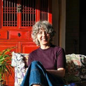 Portrait d'Elisabetta, souriante, assise chez elle dans la lumière du soleil.