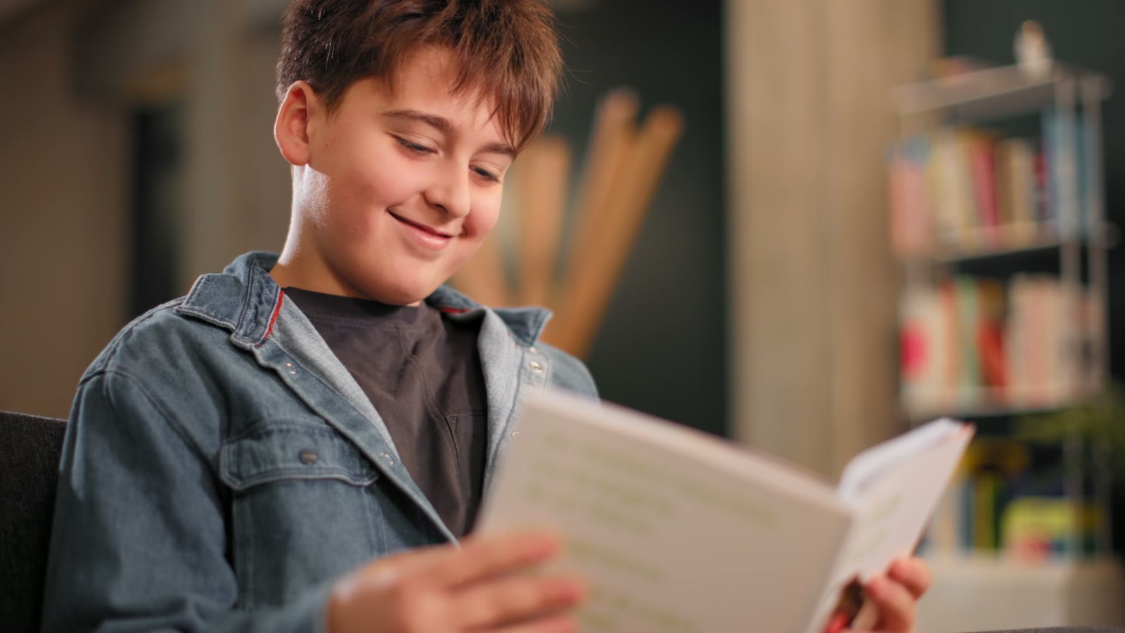 Un garçon sourit en lisant le livre L'artiste chimiste.